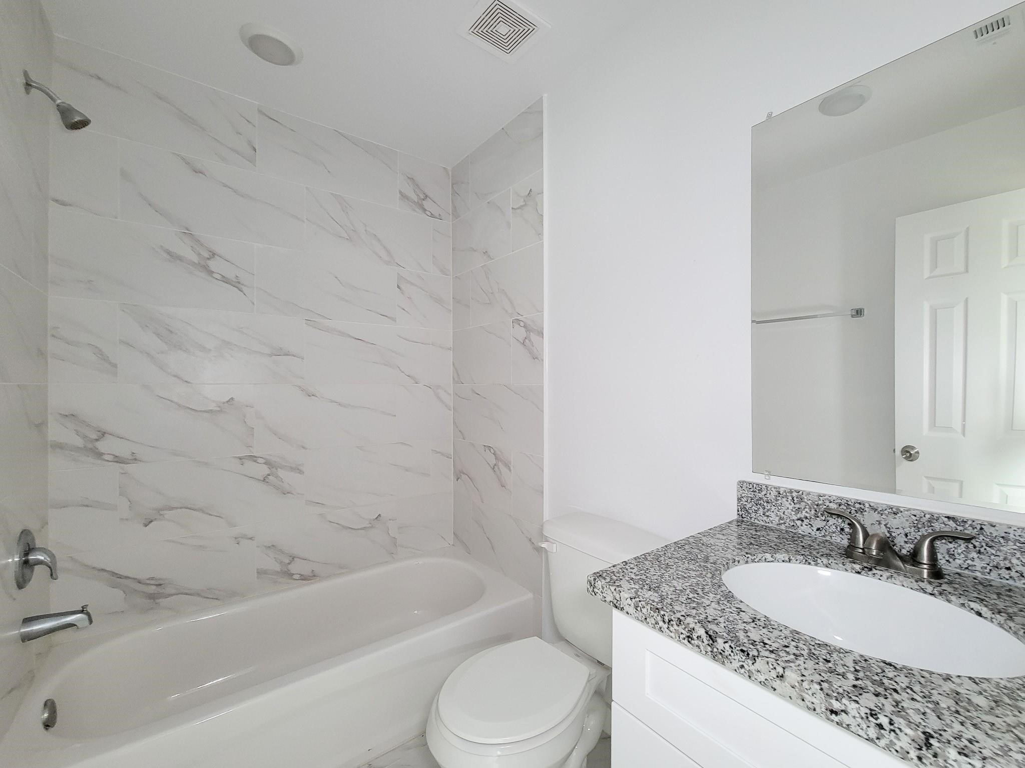 8122 Sterlingshire Street, Unit B Houston, TX 77078 - Photo 26 of 27 a bathroom with a granite countertop sink toilet and bathtub