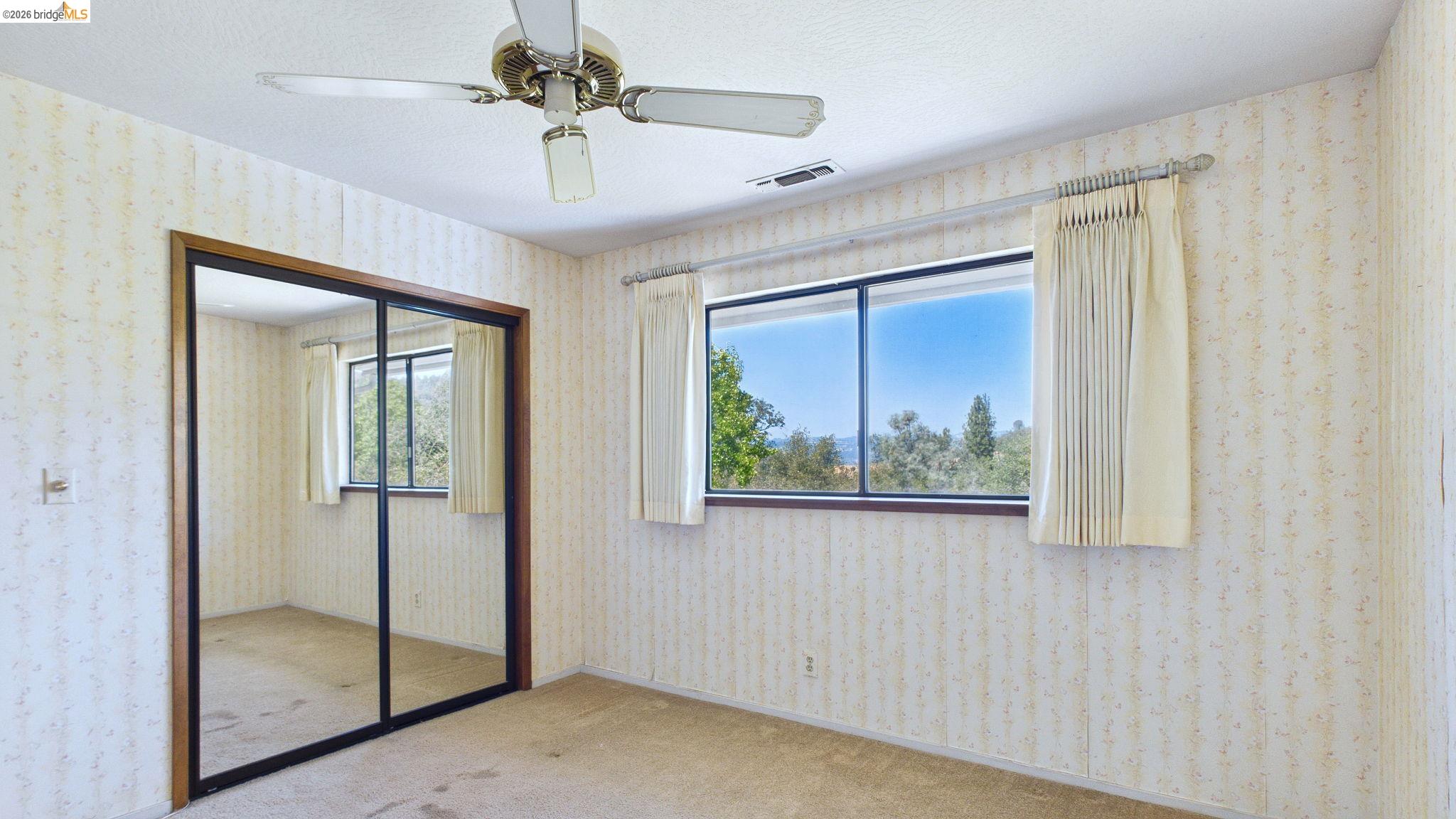 23686 Marble Quarry Road, Unit 72 Columbia, CA 95310 - Photo 29 of 35 Ceiling fan with light fixture, mirrored sliding closet doors, and window with natural light