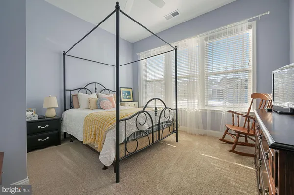 a bedroom with a bed a desk and chair with window