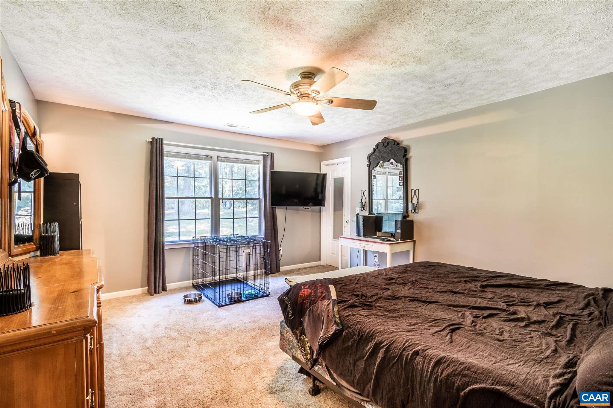196 Logtrac Road Stanardsville, VA 22973 - Photo 31 of 34 a bedroom with a large bed a flat tv screen and a dresser