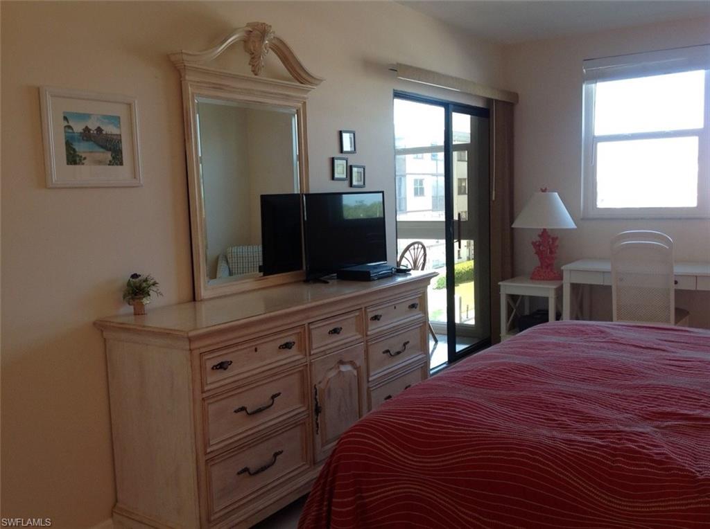 803 River Point Drive, Unit 202B Naples, FL 34102 - Photo 17 of 24 a bedroom with a bed and a flat tv screen on dresser