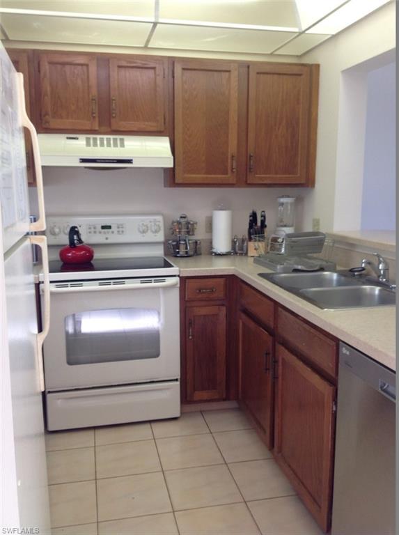 803 River Point Drive, Unit 202B Naples, FL 34102 - Photo 18 of 24 a kitchen with granite countertop a stove top oven and cabinets