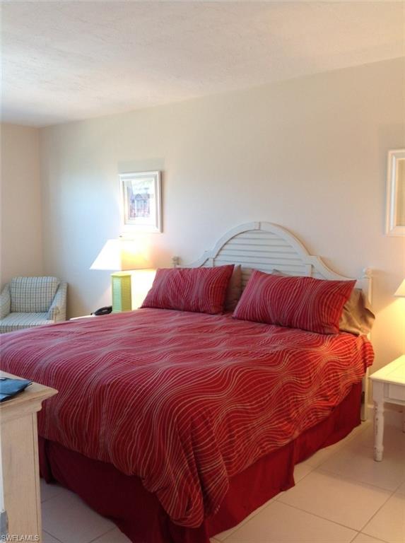 803 River Point Drive, Unit 202B Naples, FL 34102 - Photo 8 of 24 a bedroom with a bed and a lamp