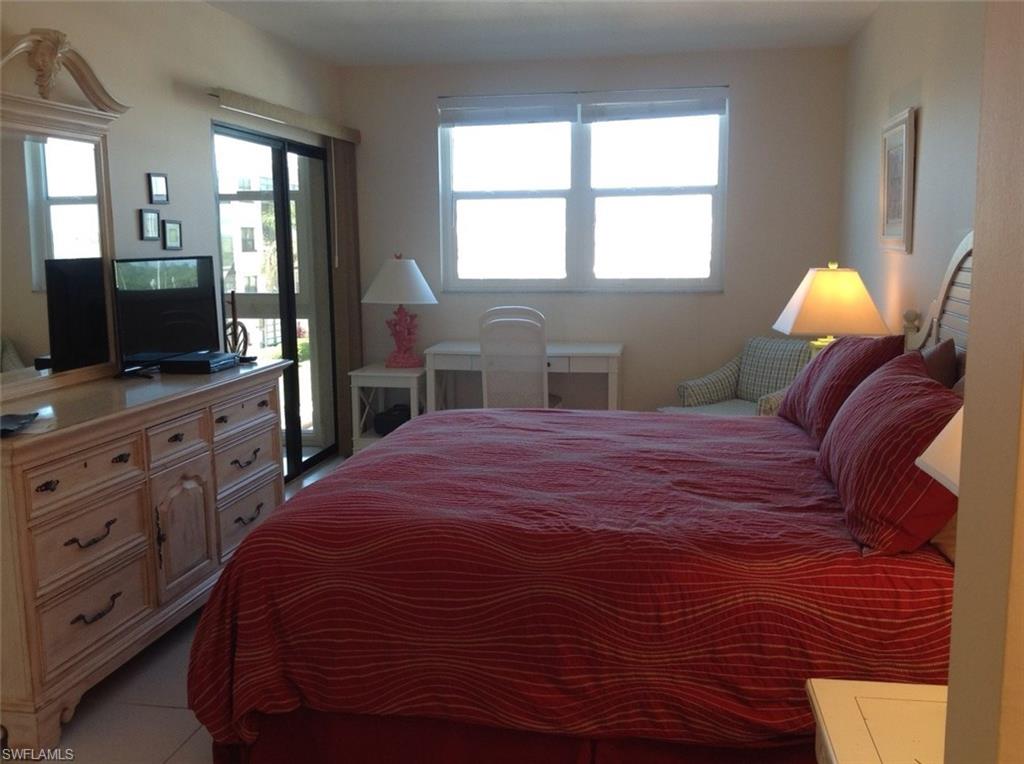 803 River Point Drive, Unit 202B Naples, FL 34102 - Photo 10 of 24 a bedroom with a bed and a flat screen tv