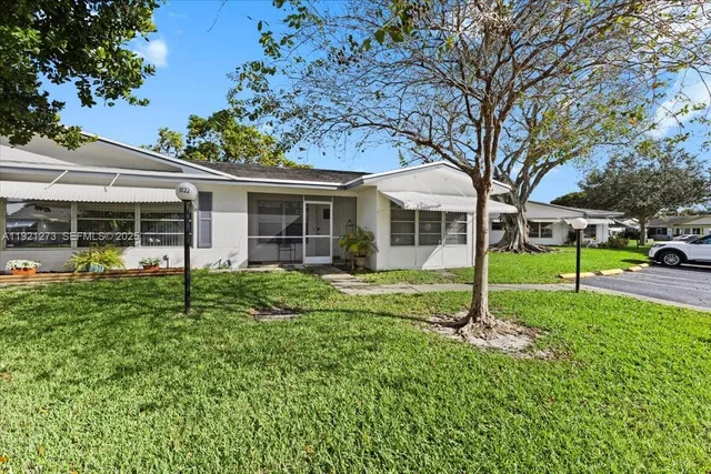 a view of a house with backyard and a tree