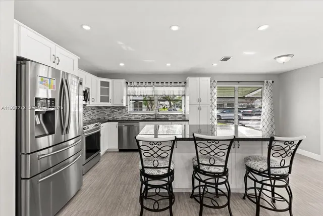a kitchen with stainless steel appliances a dining table chairs refrigerator and stove