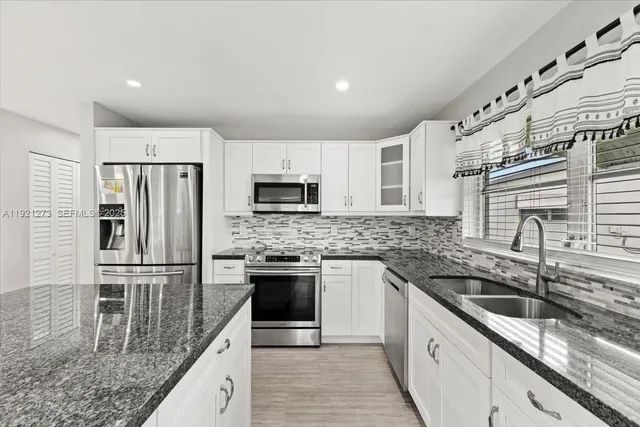 a kitchen with stainless steel appliances granite countertop a sink stove and refrigerator