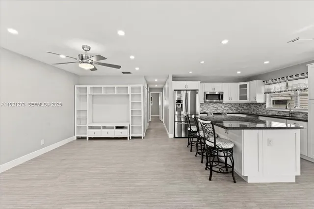 a view of kitchen with stainless steel appliances kitchen island a stove a refrigerator cabinets and living room view