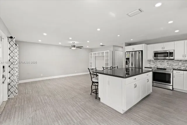 a kitchen with stainless steel appliances kitchen island granite countertop a stove top oven a sink with wooden floors