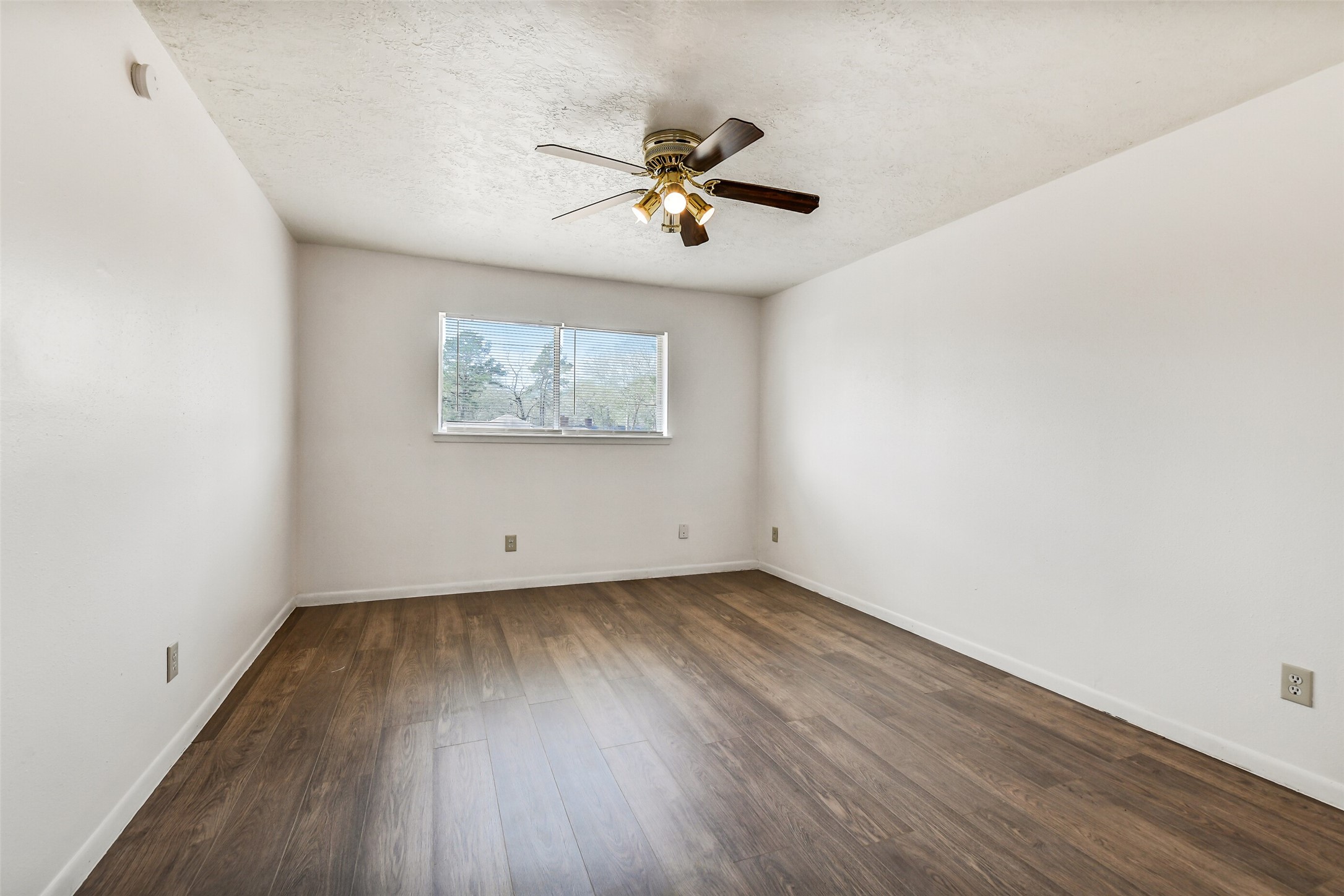 217 Lazy Lane Conroe, TX 77301 - Photo 17 of 28 an empty room with wooden floor a ceiling fan and windows