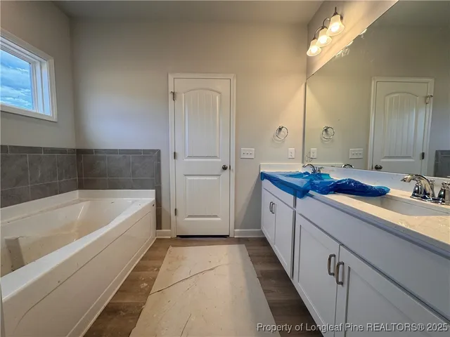 a spacious bathroom with a tub sink and mirror