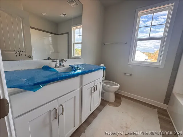 a bathroom with a granite countertop sink mirror and a toilet
