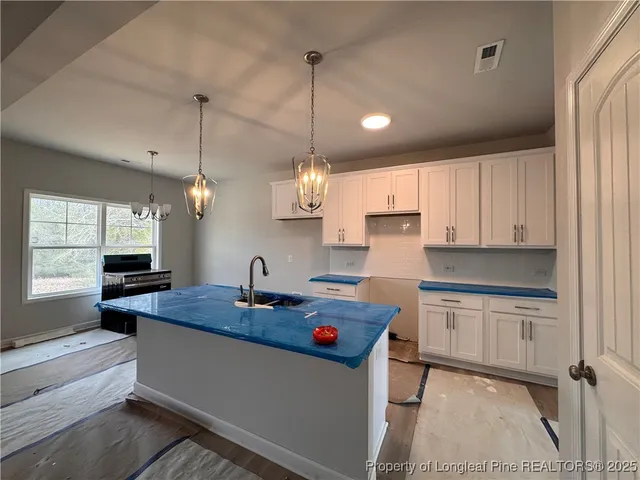 a kitchen with kitchen island granite countertop a sink a counter space appliances and cabinets