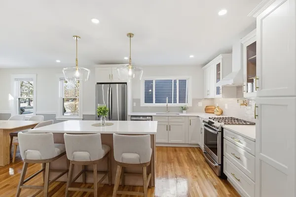 a large kitchen with kitchen island a chandelier and white cabinets