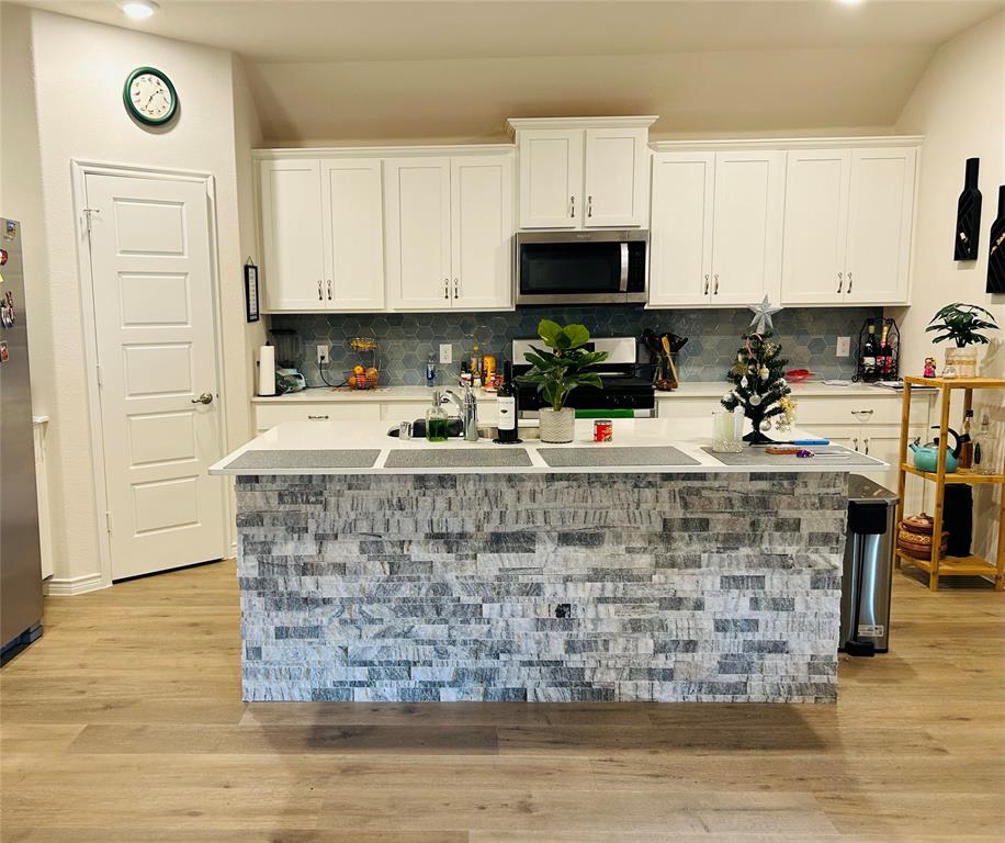 8404 Radiant Street Garland, TX 75043 - Photo 4 of 11 a kitchen with a stove a sink and a white cabinets
