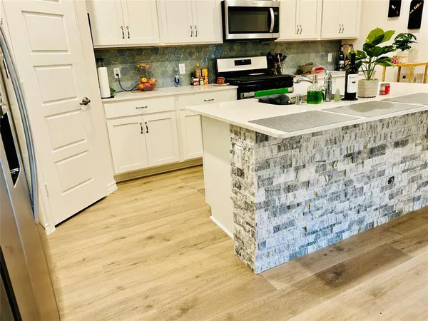 a kitchen with stainless steel appliances granite countertop a stove a sink and white cabinets