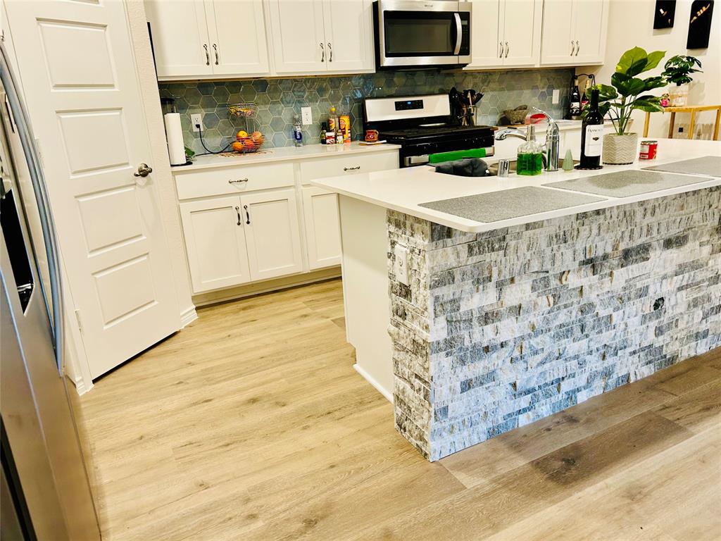 8404 Radiant Street Garland, TX 75043 - Photo 5 of 11 a kitchen with stainless steel appliances granite countertop a stove a sink and white cabinets