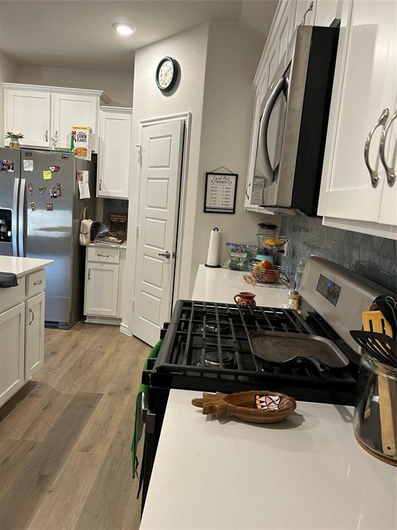 8404 Radiant Street Garland, TX 75043 - Photo 9 of 11 a kitchen with a refrigerator a stove a sink dishwasher and white cabinets with wooden floor