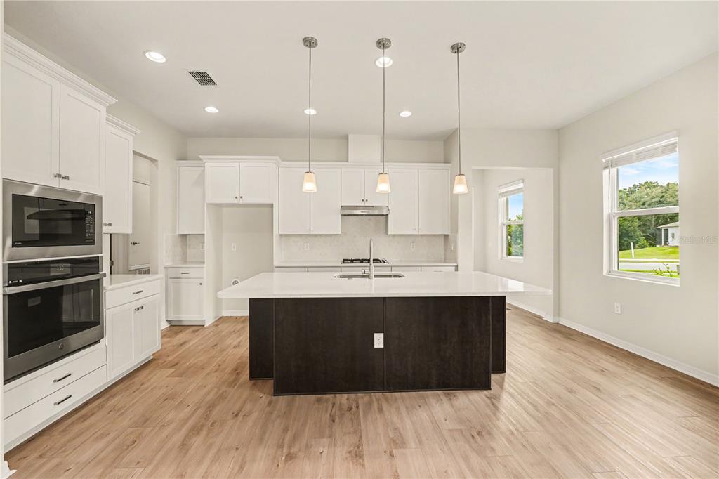 1991 Key Bay Trail Kissimmee, FL 34747 - Photo 7 of 31 a kitchen with stainless steel appliances granite countertop a sink a stove and a wooden floors