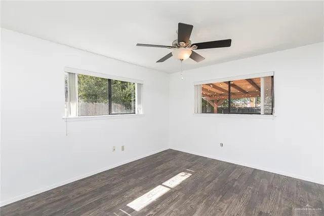 an empty room with wooden floor closet and windows