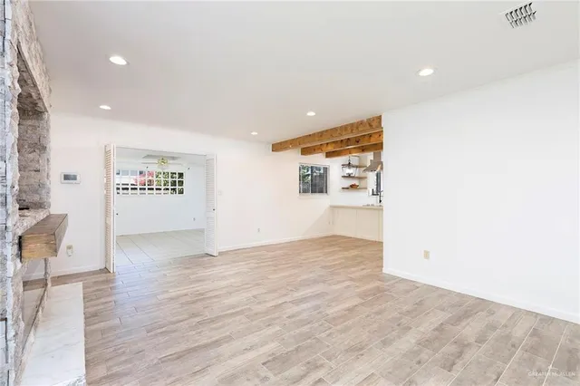 a view of an empty room with wooden floor and a window