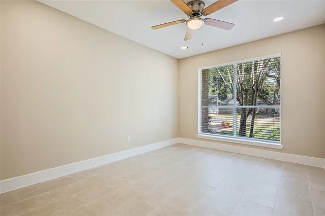 an empty room with a window and a fan