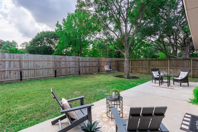 a view of a backyard with table and chairs and wooden fence