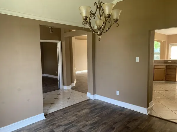 a view of a hallway with wooden floor and a chandelier