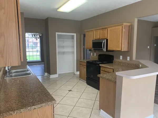 a kitchen with granite countertop a stove a sink and a refrigerator