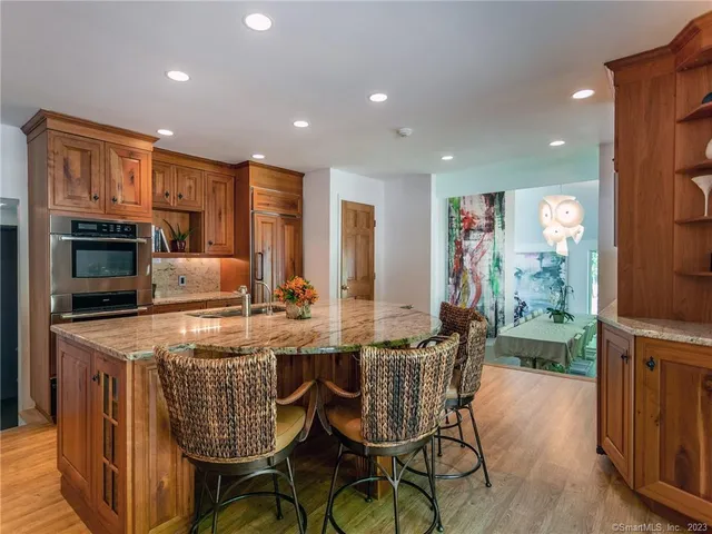 a kitchen with stainless steel appliances granite countertop a stove a refrigerator a kitchen island a couches and chairs