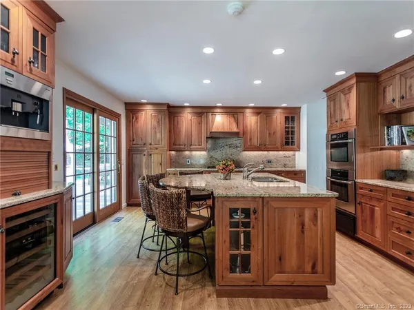 a kitchen with stainless steel appliances granite countertop a table chairs sink and cabinets