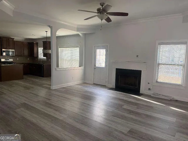 an empty room with wooden floor fireplace and windows