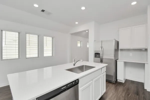 a kitchen with a sink a refrigerator and wooden floor