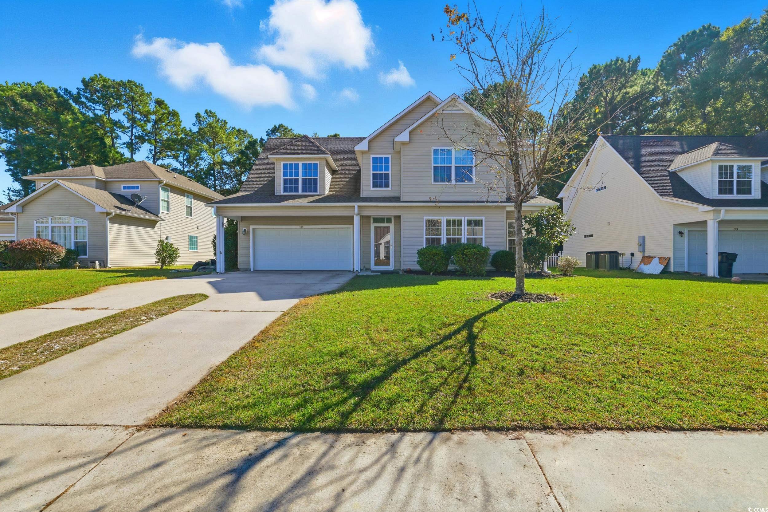 Traditional home featuring concrete driveway, a front yard, and a garage