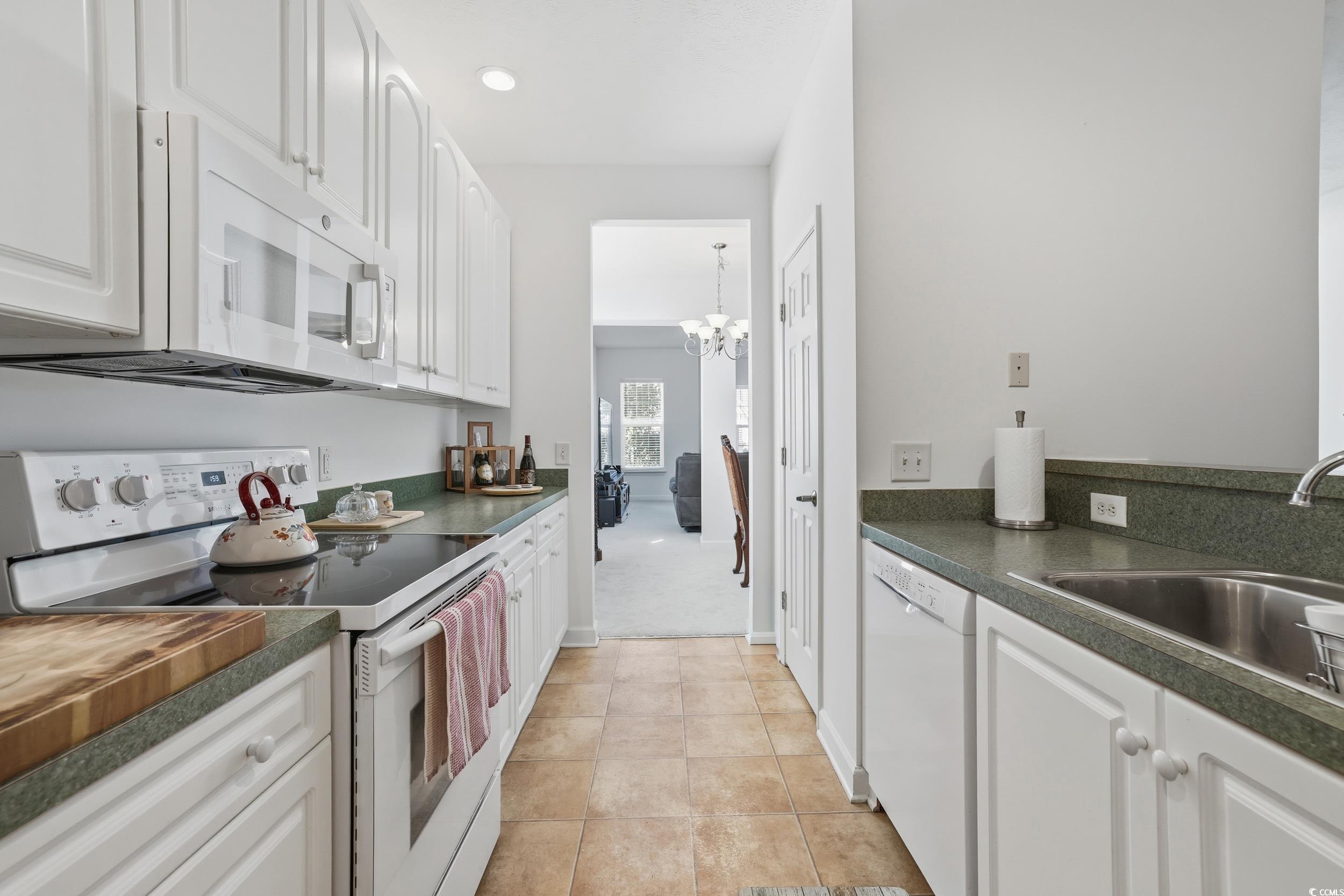 309 Meadowside Drive Little River, SC 29566 - Photo 2 of 40 Kitchen featuring white appliances, dark countertops, white cabinets, a chandelier, and light tile patterned floors