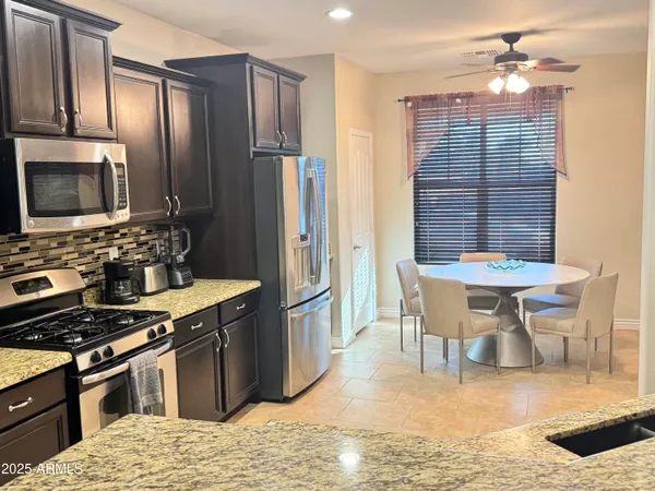 a kitchen with stainless steel appliances granite countertop a stove top oven a sink dishwasher a dining table and chairs with wooden floor