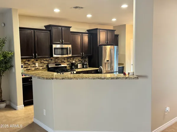 a kitchen with kitchen island granite countertop wooden cabinets a refrigerator and a sink
