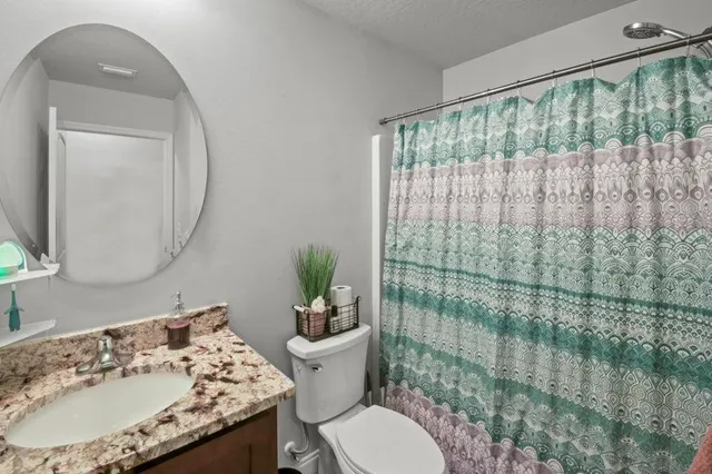a bathroom with a granite countertop sink a toilet and a mirror