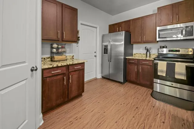 a kitchen with stainless steel appliances granite countertop a stove a refrigerator and a sink with wooden floor