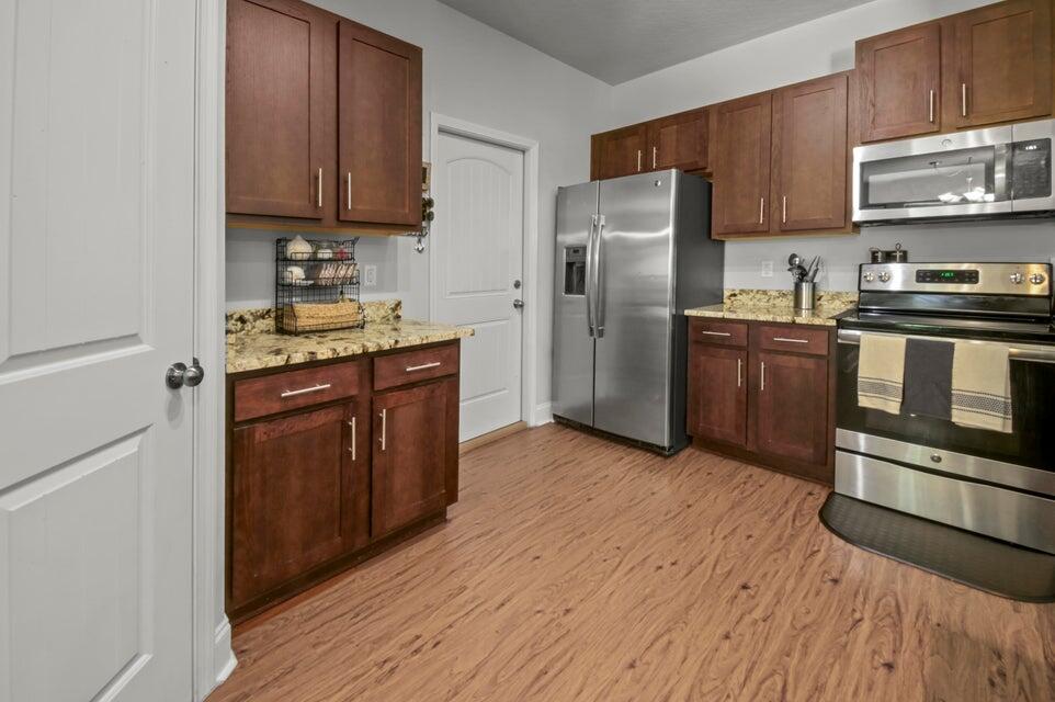300 Cassady Lane Crestview, FL 32539 - Photo 9 of 25 a kitchen with stainless steel appliances granite countertop a stove a refrigerator and a sink with wooden floor