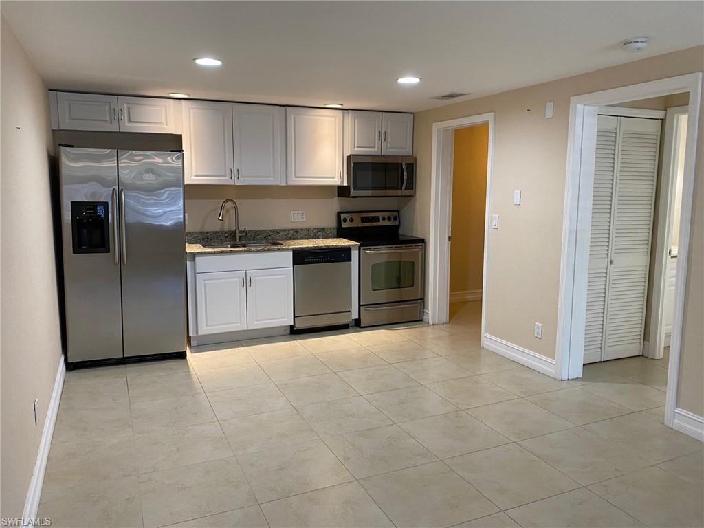 5389 Treetops Drive Naples, FL 34113 - Photo 1 of 8 Kitchen featuring stainless steel appliances, recessed lighting, white cabinetry, light tile patterned floors, and dark stone countertops