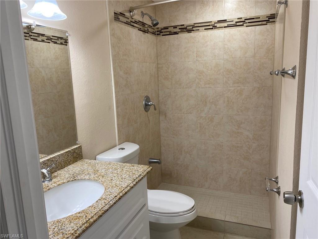 5389 Treetops Drive Naples, FL 34113 - Photo 3 of 8 Bathroom with a textured wall, vanity, and a shower stall