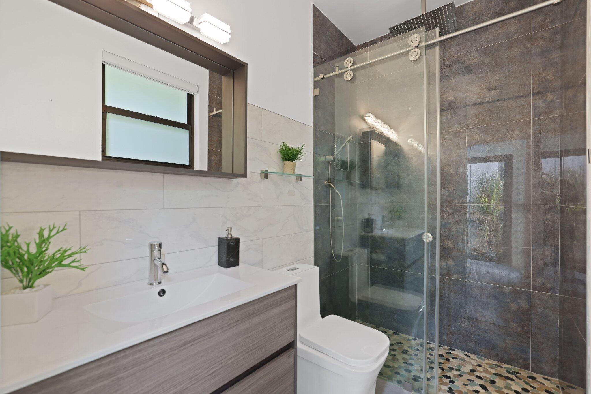 4265 Southwest 185th Avenue Miramar, FL 33029 - Photo 51 of 64 a bathroom with a sink a mirror a glass door a toilet and shower