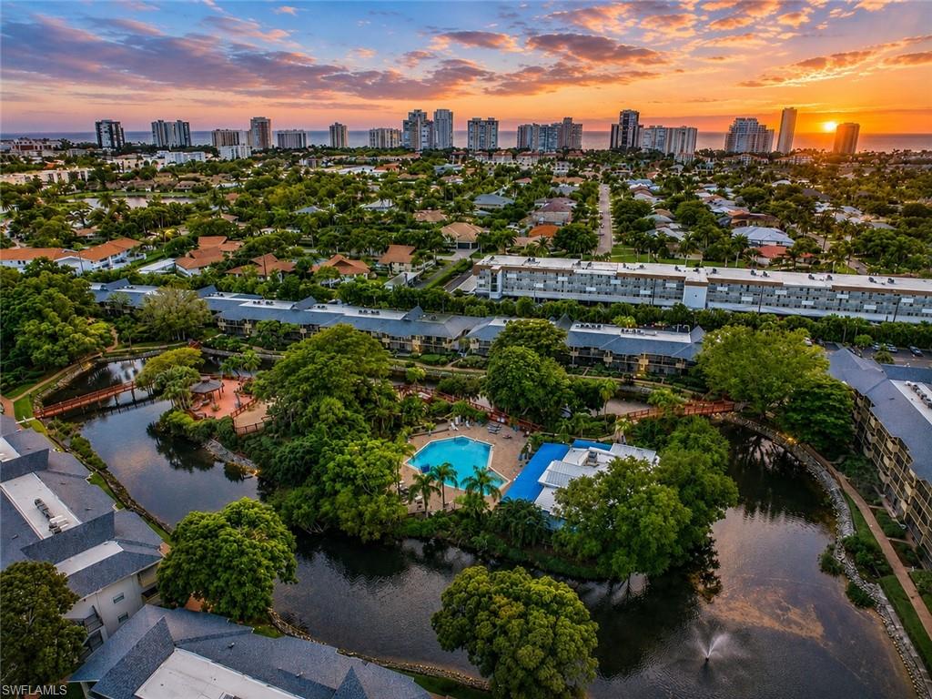 600 Neapolitan Way, Unit 449 Naples, FL 34103 - Photo 2 of 44 Community with multiple residential buildings, a central water feature, and extensive mature landscaping