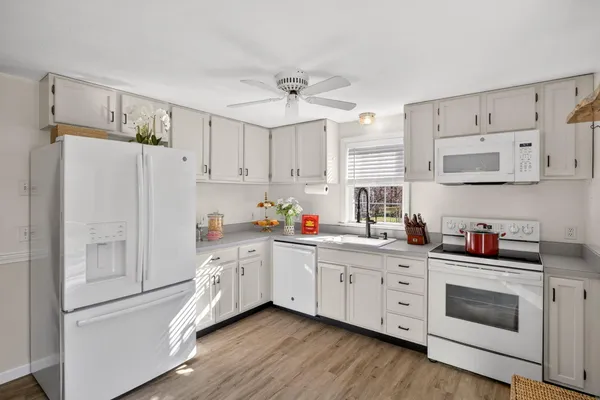a kitchen with stainless steel appliances white cabinets and wooden floors