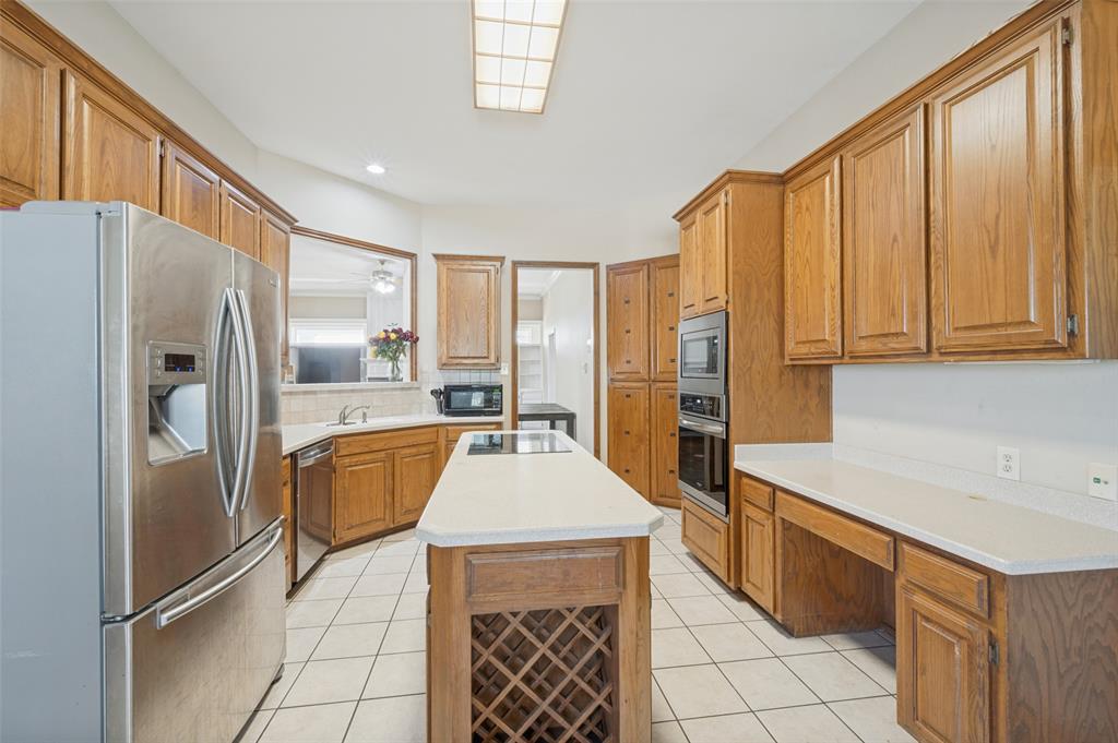 1601 East Blackjack Road East Pilot Point, TX 76258 - Photo 6 of 30 Kitchen with wood-finish cabinetry, stainless steel appliances, a center island with integrated cooktop, stone-finish countertops, and tile flooring