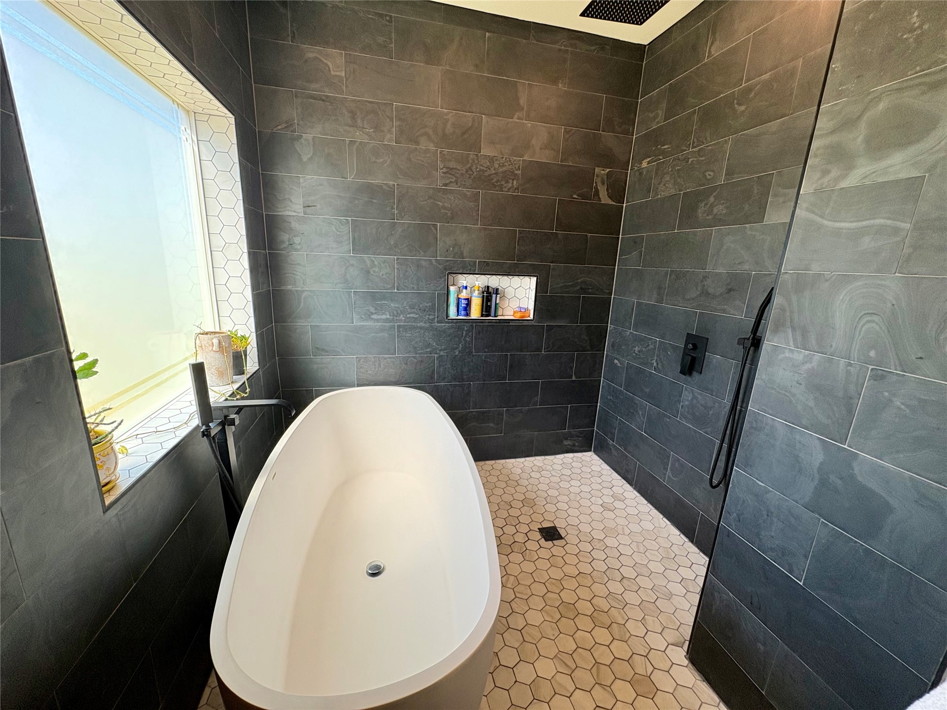 313 Nauvoo Hills Road Caddo, OK 74729 - Photo 15 of 41 Freestanding soaking tub, large format tile walls, hexagonal tile flooring, built-in shower niche, and a rain shower head