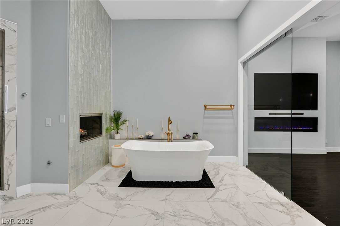 6 Rue Du Ville Henderson, NV 89011 - Photo 61 of 99 This spacious primary bathroom features a standalone tub and a sleek fireplace, creating a serene retreat.