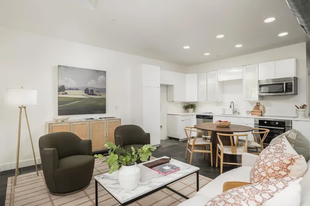 a living room with furniture a flat screen tv and kitchen view