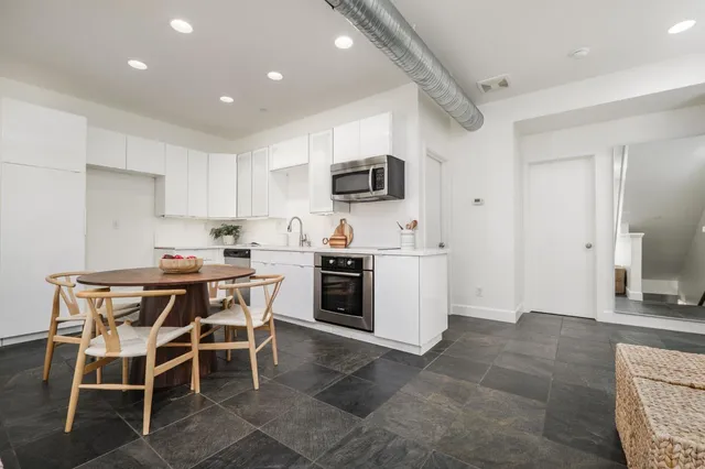 a kitchen with a dining table chairs and a refrigerator
